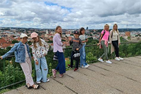 Vaikai, dainuojantys chore, su Vilniaus panorama fone