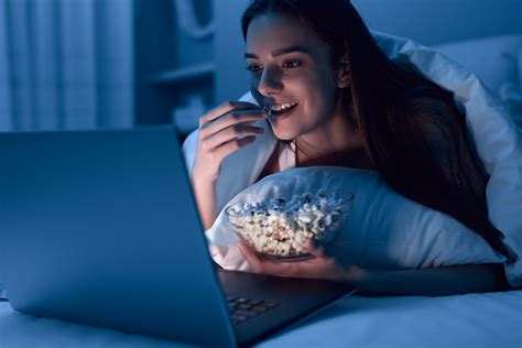 Moteris valgo pistacijas prieš miegą, iliustruojanti lengvą užkandį