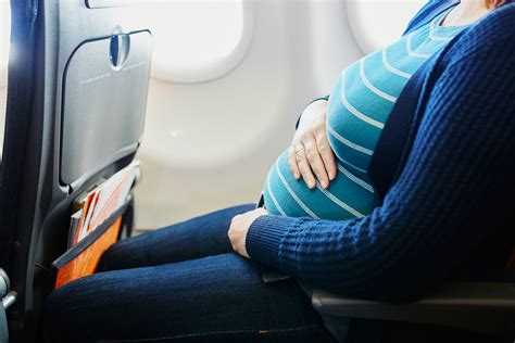 Nėščia moteris su lagaminu prie lėktuvo
