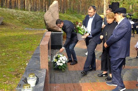 Gedintys žmonės prie paminklo, atspindys liūdesį ir pagarbą