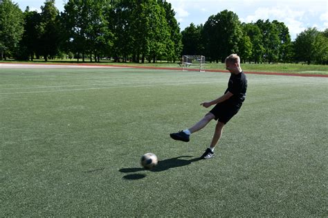 Jaunas berniukas, žaidžiantis amerikietišką futbolą parke