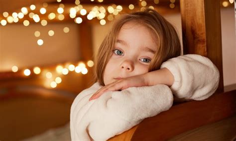 Liūdnas vaikas sėdi ant sofos, ieško paguodos