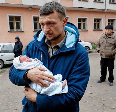 Tėtis laiko kūdikį ant rankų, motina šypsosi