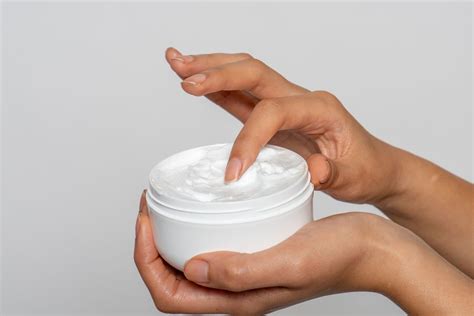 Moters ranka tepa drėkinamąjį kremą ant pilvo