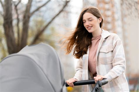 Mama su kūdikio vežimėliu intensyviai vaikšto parke