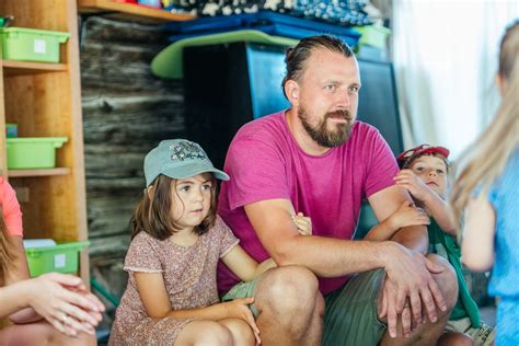 Vaikai sėdi ratu lauke ir klauso auklėtojos