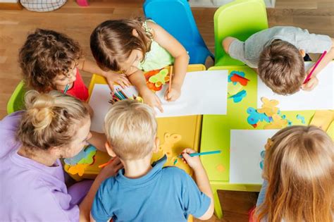 Vaikai darželyje rašo arba piešia lapeliuose su nebaigtais sakiniais