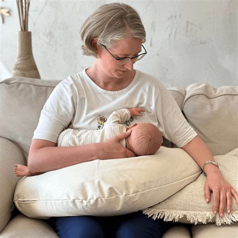 Moteris su kūdikiu, besinaudojanti maitinimo pagalve