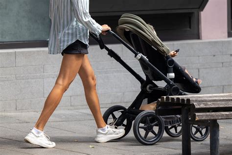 tėvai stumia vežimėlį parke