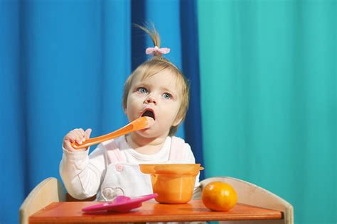 Sveikas 6 mėnesių kūdikis prie stalo su daržovių koše