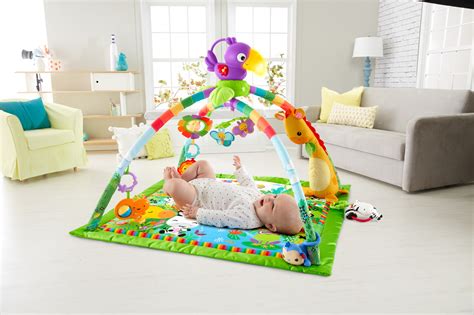 Kūdikis žaidžia ant Fisher Price Rainforest kilimėlio su pakabinamais žaislais