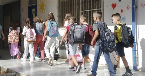 Moksleiviai su kuprinėmis eina į mokyklą