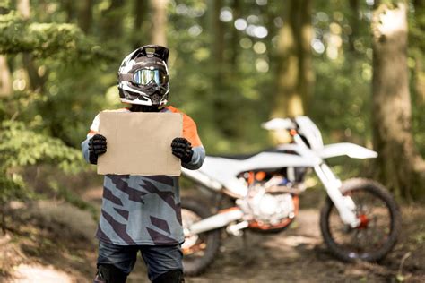 Vaikas važiuojantis krosiniu motociklu miške