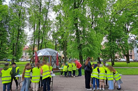 Vaikų grupė su ryškiomis saugumo liemenėmis, einanti pasivaikščioti