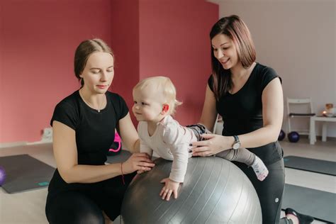 Tėvai su kūdikiu kineziterapijos užsiėmimo metu