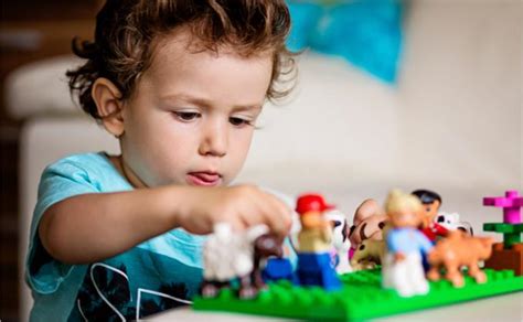 Vaikas žaidžia su LEGO® DUPLO® kaladėlėmis, kurdamas darželio sceną