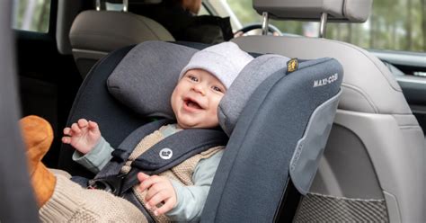 Šeima su vaiku automobilyje, įrengianti automobilinę kėdutę