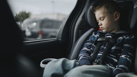 vaikas su kombinezonu automobilinėje kėdutėje