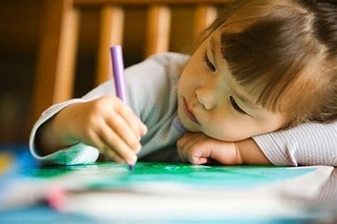 Vaikas piešia, o šalia guli atversta knyga, rodanti kūrybinį procesą