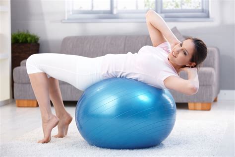 Moteris sėdi ant mankštos kamuolio ir atlieka pratimus