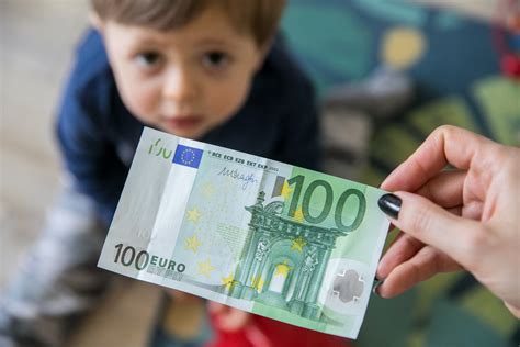Moters rankos laikančios banknotus su vaiko priežiūros išmokų simboliais