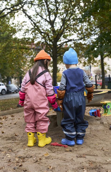 Vaikai žaidžia baloje su lietaus rūbais