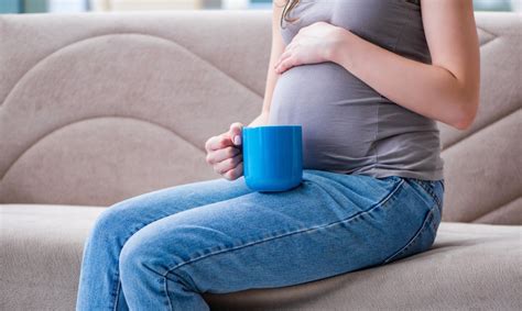 Nėščia moteris, geriantis stiklinę vandens