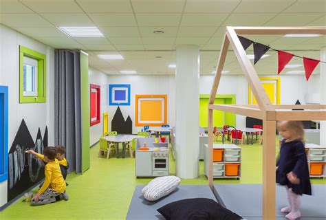 Modernios ikimokyklinės įstaigos interjeras su žaidimų zonomis.