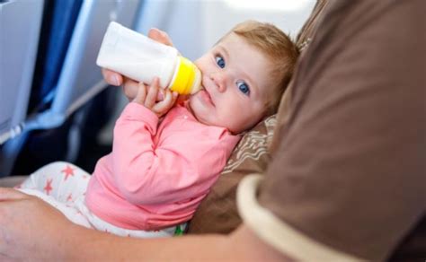 kūdikis lėktuve ant tėvų kelių su saugos diržu