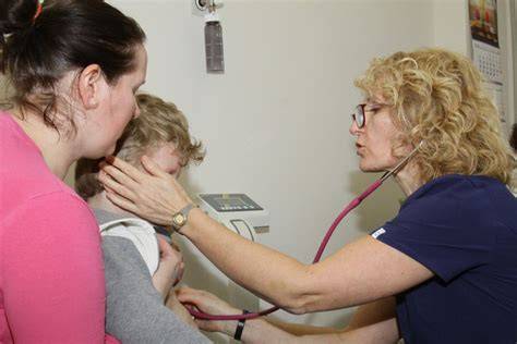 Gydytojas pediatras konsultuojantis mažąjį pacientą kabinete