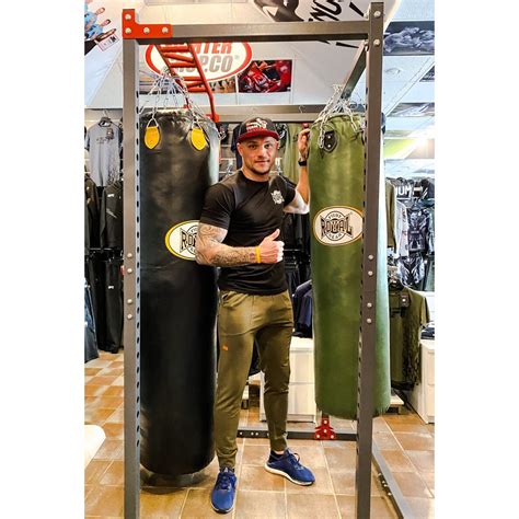 Vaikas atlieka bokso smūgius į bokso maišą su trenerio priežiūra