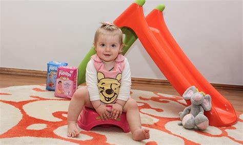 Vaikas sėdi ant puoduko su knyga