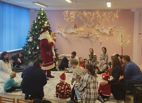 Vaikai dainuoja prie Kalėdų eglutės darželio salėje