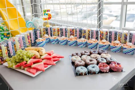 vaikų gimtadienio stalas darželyje su vaisiais ir dekoracijomis