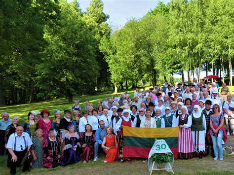 Grupė įvairaus amžiaus žmonių juokiasi ir bendrauja, sustoję ratu