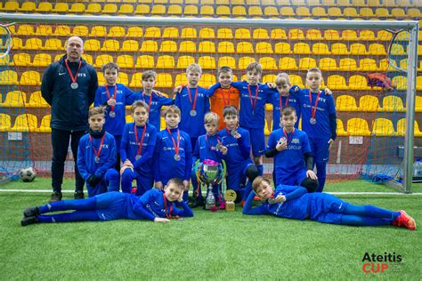 Nuotrauka iš futbolo aikštės su žaidžiančiais vaikais ir treneriais 