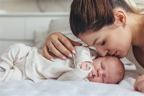 mama švelniai migdo kūdikį lopšinėje
