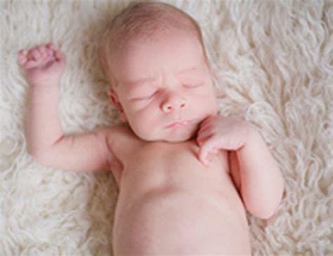 kūdikis su susiraukusiomis kojytėmis prie pilvuko