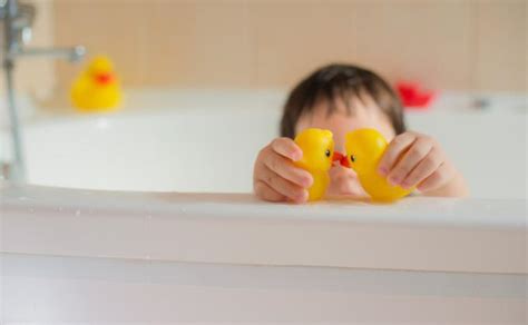 Vaikas maudosi ir naudoja prausiklį