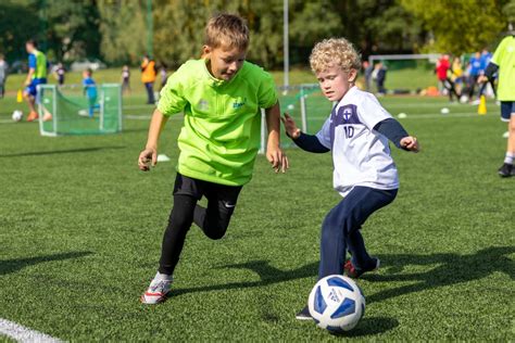 Vaikai žaidžiantys futbolą lauke, besimokantys komandinio darbo