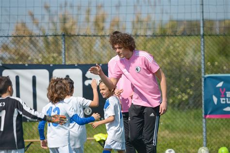 Tėvai ir treneris stebi futbolo treniruotę, palaikydami vaikus