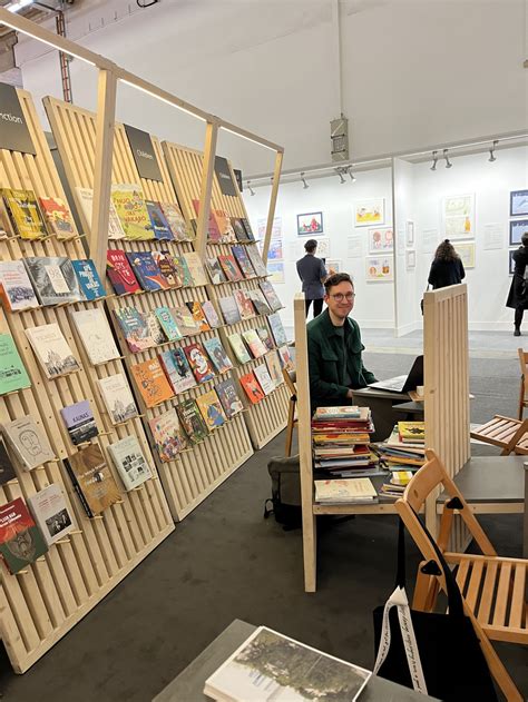 Knygų mugės stendas su vaikų literatūros naujienomis ir besišypsančiais lankytojais
