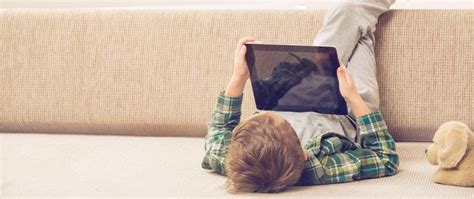 vaikas, žiūrintis į planšetinį kompiuterį