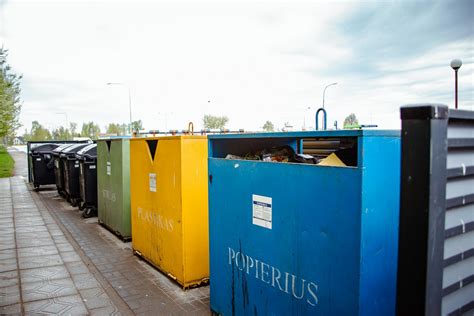 vaikai rūšiuoja atliekas spalvotuose konteineriuose