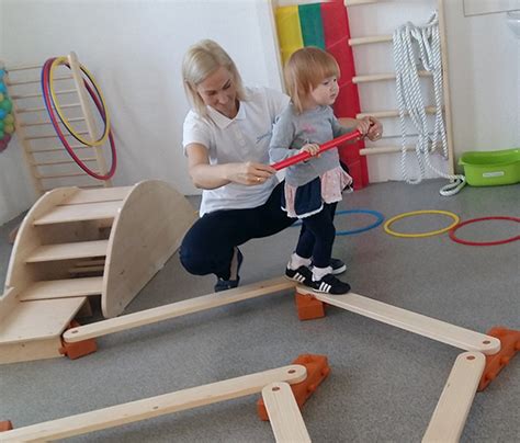 vaikas atlieka pusiausvyros pratimą ant medinės platformos