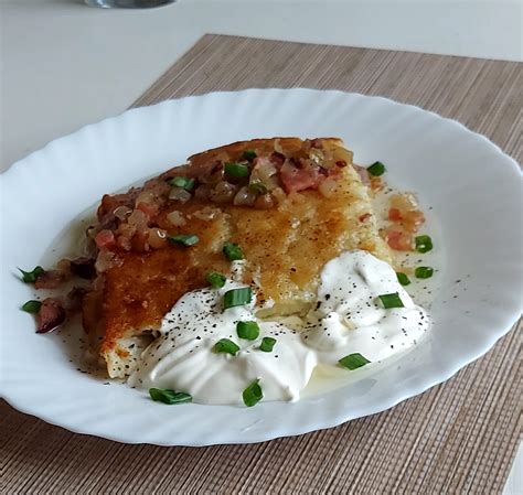 lėkštė su auksiniais, traškiais bulviniais blynais, patiektais su grietine ir žalumynais