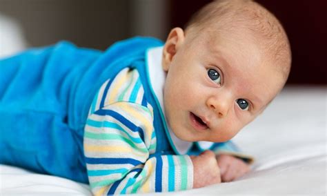 kūdikis gulintis ant pilvo su padėtomis rankytėmis